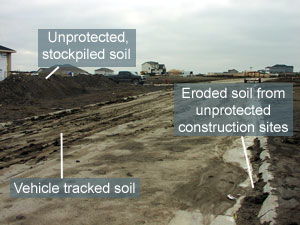 Image showing several types of erosion on a construction site. Specific items pointed out are unprotected, stockpiled soil; soil tracked into street by construction vehicles, and soil from the unprotected site in the street.